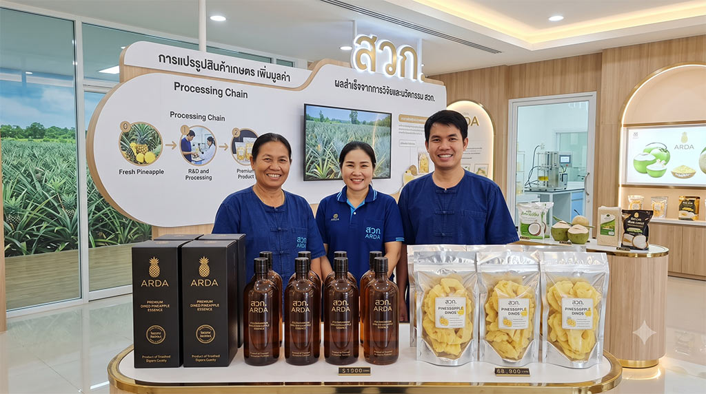 กลุ่มเกษตรกรและเจ้าหน้าที่ สวก. ยืนยิ้มแย้มด้านหลังเคาน์เตอร์โชว์สินค้าแปรรูปจากสับปะรด เช่น สับปะรดอบแห้งในถุงฟอยล์ และน้ำสับปะรดสกัดเข้มข้นบรรจุขวด ภายใต้โครงการวิจัยและนวัตกรรมของสำนักงานพัฒนาการวิจัยการเกษตร (สวก. หรือ ARDA)